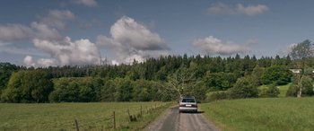 Movie still from “Border” (2018), directed by Ali Abbasi – A car driving down a dirt road near a forest; Extreme Wide shot, Low angle