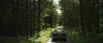 Movie still from “Border” (2018), directed by Ali Abbasi – A car driving down a road in the middle of a forest; Extreme Wide shot, High angle
