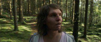 Movie still from “Border” (2018), directed by Ali Abbasi – A person with long hair is in the woods; Close Up shot, Over the shoulder angle