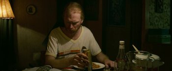 Movie still from “Border” (2018), directed by Ali Abbasi – A man sitting at a table with a plate of food; Medium shot, Over the shoulder angle