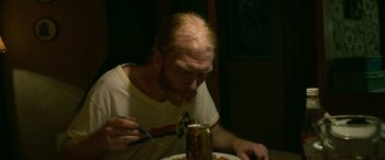 Movie still from “Border” (2018), directed by Ali Abbasi – A man eating a can of beer while sitting at a dinner table; Close Up shot, High angle