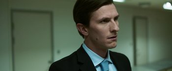 Movie still from “Border” (2018), directed by Ali Abbasi – A person wearing a suit and tie; Close Up shot, Over the shoulder angle