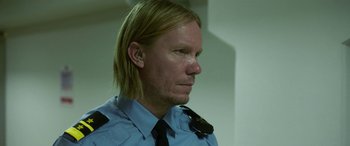 Movie still from “Border” (2018), directed by Ali Abbasi – A man with long blonde hair wearing a police uniform; Close Up shot, Over the shoulder angle