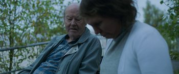 Movie still from “Border” (2018), directed by Ali Abbasi – An older man and a younger woman sitting next to each other on a park bench; Medium shot, Over the shoulder angle