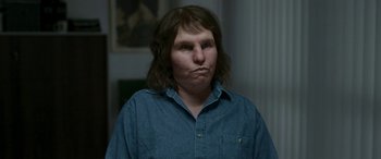 Movie still from “Border” (2018), directed by Ali Abbasi – A person with long hair and a blue shirt; Close Up shot, High angle