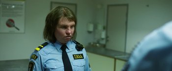 Movie still from “Border” (2018), directed by Ali Abbasi – A man in a police uniform with long brown hair; Close Up shot, Over the shoulder angle