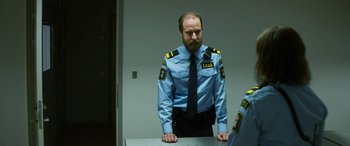 Movie still from “Border” (2018), directed by Ali Abbasi – A man in a blue shirt and black tie standing in front of a mirror; Medium shot, Over the shoulder angle