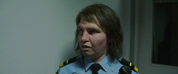 Movie still from “Border” (2018), directed by Ali Abbasi – A woman wearing a uniform and a black tie; Close Up shot, Low angle