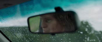 Movie still from “Border” (2018), directed by Ali Abbasi – A reflection of a man in a rear view mirror of a car; Extreme Close Up shot, Over the shoulder angle