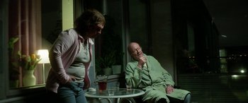 Movie still from “Border” (2018), directed by Ali Abbasi – An older man and a woman sitting at a table; Medium shot, Over the shoulder angle
