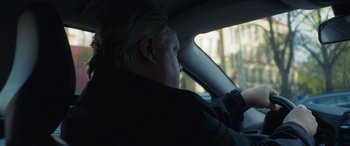 Movie still from “Border” (2018), directed by Ali Abbasi – An older man sitting in the driver's seat of a car; Close Up shot, Over the shoulder angle