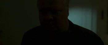 Movie still from “Border” (2018), directed by Ali Abbasi – A man in a black shirt is in a dark room; Close Up shot, High angle