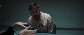 Movie still from “Border” (2018), directed by Ali Abbasi – A man is looking at a video camera in front of him; Close Up shot, Over the shoulder angle