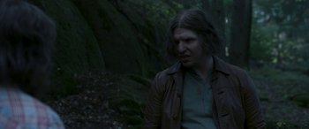 Movie still from “Border” (2018), directed by Ali Abbasi – A man with long brown hair wearing a brown jacket; Close Up shot, Over the shoulder angle