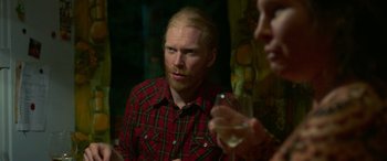 Movie still from “Border” (2018), directed by Ali Abbasi – A man in a plaid shirt is holding a glass of wine; Close Up shot, Over the shoulder angle