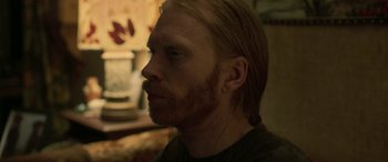 Movie still from “Border” (2018), directed by Ali Abbasi – A person with long hair and a beard; Close Up shot, Over the shoulder angle