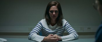 Movie still from “Border” (2018), directed by Ali Abbasi – A woman sitting at a table with her hands crossed; Medium shot, Low angle