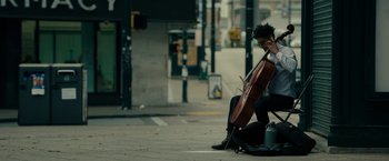 A man sitting on the ground holding a cello
