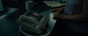Movie still from “Breaking” (2022), directed by Abi Damaris Corbin – A person is sitting at a desk with a phone; Extreme Close Up shot, High angle