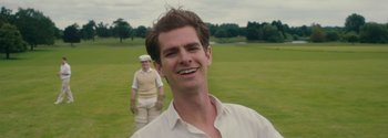 Movie still from “Breathe” (2017), directed by Andy Serkis – A man smiling while standing next to another man in a field; Close Up shot, Over the shoulder angle