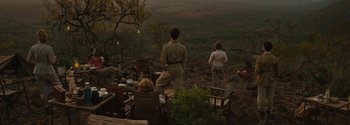 Movie still from “Breathe” (2017), directed by Andy Serkis – A group of people standing on top of a grass covered field; Wide shot, Over the shoulder angle
