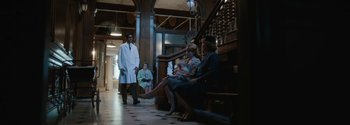 Movie still from “Breathe” (2017), directed by Andy Serkis – A group of people sitting on steps in front of a staircase; Wide shot, Low angle