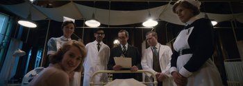 Movie still from “Breathe” (2017), directed by Andy Serkis – A group of doctors standing next to each other in a room; Medium shot, Low angle