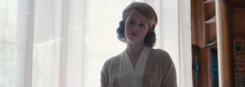 Movie still from “Breathe” (2017), directed by Andy Serkis – A young woman in a white shirt and a beige cardigan; Close Up shot, Over the shoulder angle