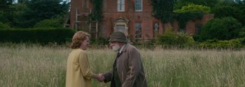 Movie still from “Breathe” (2017), directed by Andy Serkis – An older man and a young woman shaking hands in front of a brick building; Medium shot, Over the shoulder angle