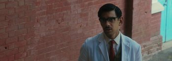 Movie still from “Breathe” (2017), directed by Andy Serkis – A man wearing a suit and tie standing in front of a brick wall; Close Up shot, Over the shoulder angle