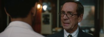 Movie still from “Breathe” (2017), directed by Andy Serkis – An older man wearing glasses and a suit and tie; Close Up shot, Over the shoulder angle