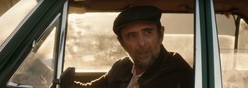 Movie still from “Breathe” (2017), directed by Andy Serkis – A person wearing a hat in a car; Close Up shot, Over the shoulder angle