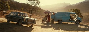 Movie still from “Breathe” (2017), directed by Andy Serkis – A man and a dog sitting on the ground next to a truck; Wide shot, Over the shoulder angle