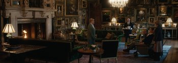 Movie still from “Breathe” (2017), directed by Andy Serkis – A man standing in a living room next to a round table; Wide shot, High angle