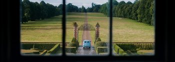 Movie still from “Breathe” (2017), directed by Andy Serkis – An old blue van parked in front of an entrance to a garden; Extreme Wide shot, High angle