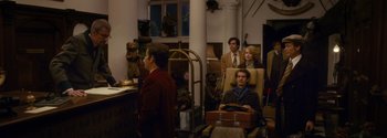 Movie still from “Breathe” (2017), directed by Andy Serkis – A group of people standing around in a room; Wide shot, Over the shoulder angle