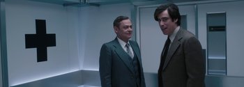 Movie still from “Breathe” (2017), directed by Andy Serkis – A man in a suit standing next to another man in a suit; Medium shot, Low angle