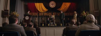 Movie still from “Breathe” (2017), directed by Andy Serkis – A group of people sitting on a stage; Wide shot, Low angle