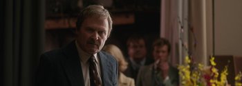 Movie still from “Breathe” (2017), directed by Andy Serkis – A man in a suit and tie standing in front of a group of people; Close Up shot, Over the shoulder angle