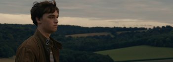 Movie still from “Breathe” (2017), directed by Andy Serkis – A woman standing in front of a lush green field; Medium shot, Low angle