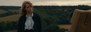 Movie still from “Breathe” (2017), directed by Andy Serkis – A woman standing in front of a lush green hillside; Medium shot, Over the shoulder angle