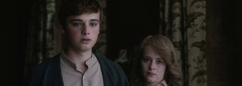 Movie still from “Breathe” (2017), directed by Andy Serkis – A young man standing next to a young woman in a room; Close Up shot, Over the shoulder angle