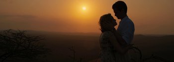 Movie still from “Breathe” (2017), directed by Andy Serkis – A man and a woman standing next to each other in front of a sunset; Medium shot, Low angle