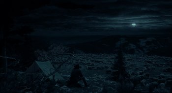 Movie still from “Brokeback Mountain” (2005), directed by Ang Lee – A man sitting on a rock in the dark at night; Extreme Wide shot, High angle