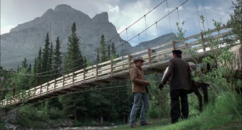 Movie still from “Brokeback Mountain” (2005), directed by Ang Lee – Two men are standing on the grass near a bridge; Wide shot, Low angle