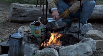 Movie still from “Brokeback Mountain” (2005), directed by Ang Lee – A person cooking food over an open fire; Medium shot, High angle