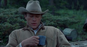 Movie still from “Brokeback Mountain” (2005), directed by Ang Lee – A man wearing a cowboy hat and holding a cup; Medium shot, Low angle