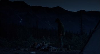 Movie still from “Brokeback Mountain” (2005), directed by Ang Lee – A man standing next to a campfire in the dark; Wide shot, Over the shoulder angle