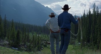 Movie still from “Brokeback Mountain” (2005), directed by Ang Lee – Two men in cowboy hats standing in a field with mountains in the background; Wide shot, Low angle