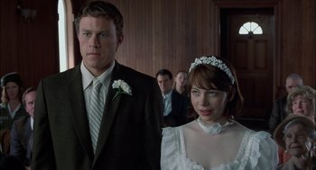 Movie still from “Brokeback Mountain” (2005), directed by Ang Lee – A man and a woman standing next to each other in front of other people; Close Up shot, Low angle